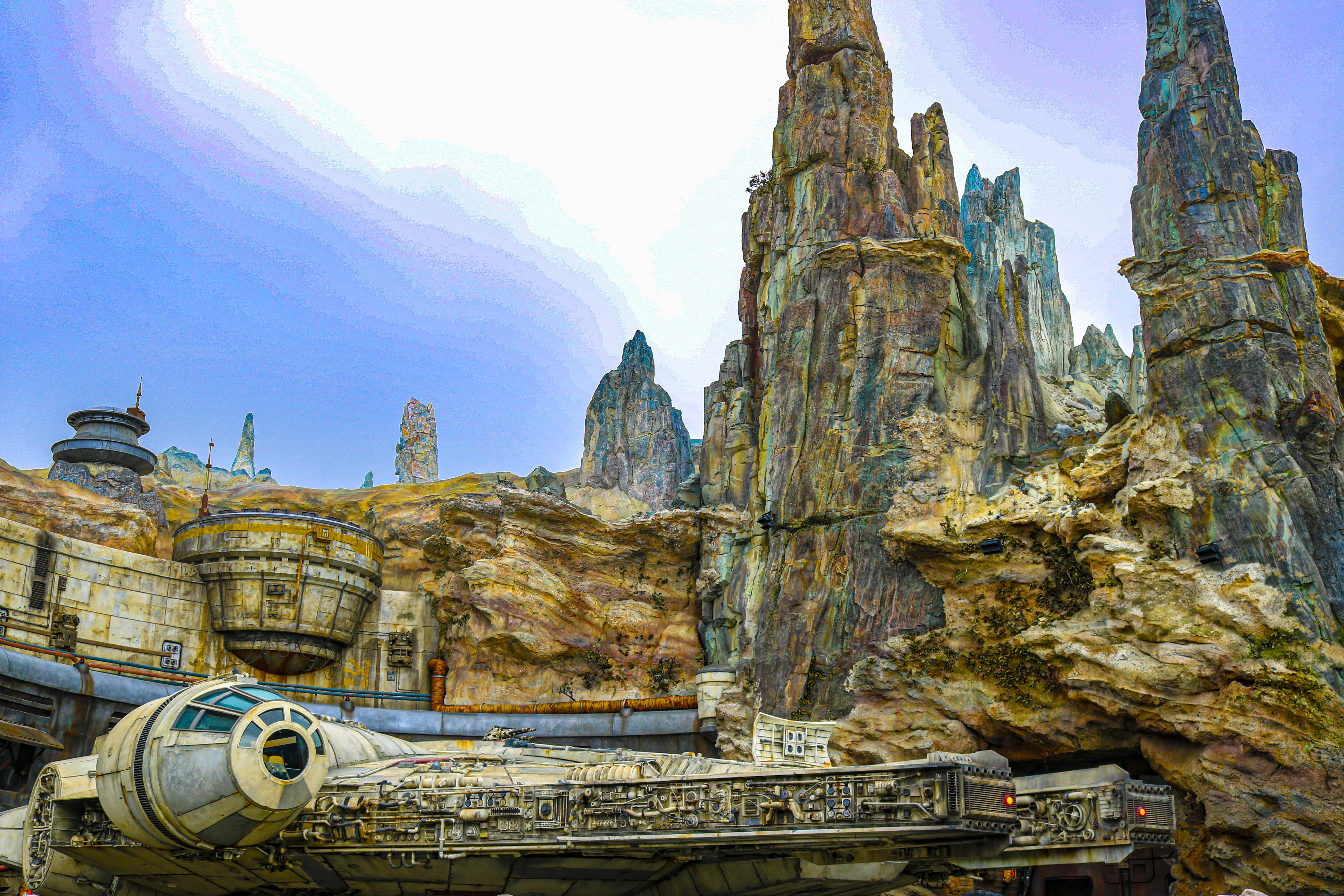 The sun peaks through the misty clouds beyond Black Spire Outpost's Spaceport at Star Wars: Galaxy's Edge. 